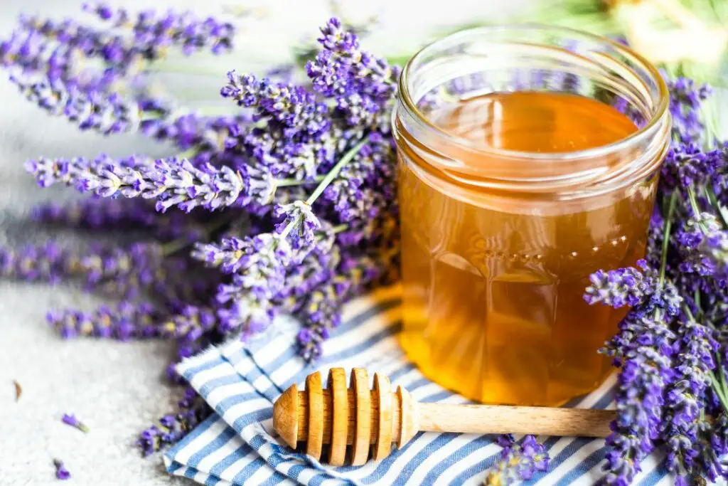 a jar of honey surrounded by lavender